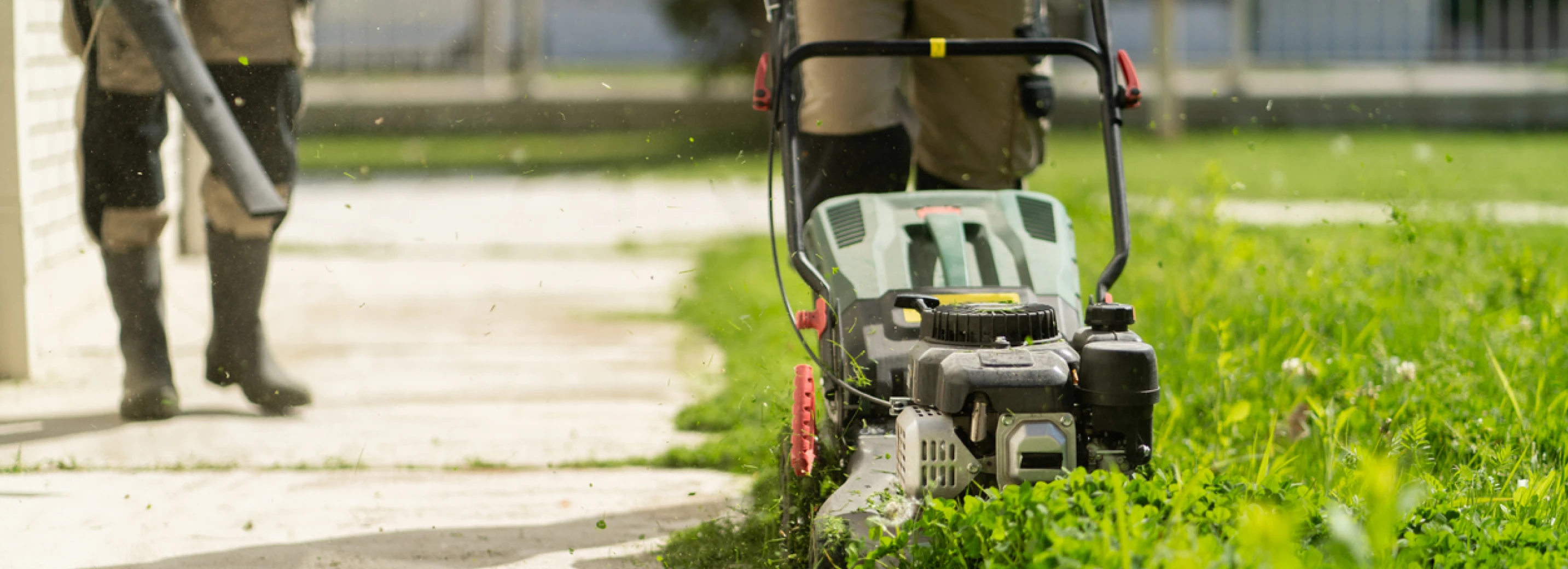 Landscaping company mowing a lawn and blowing grass off the sidewalk spreading weeds