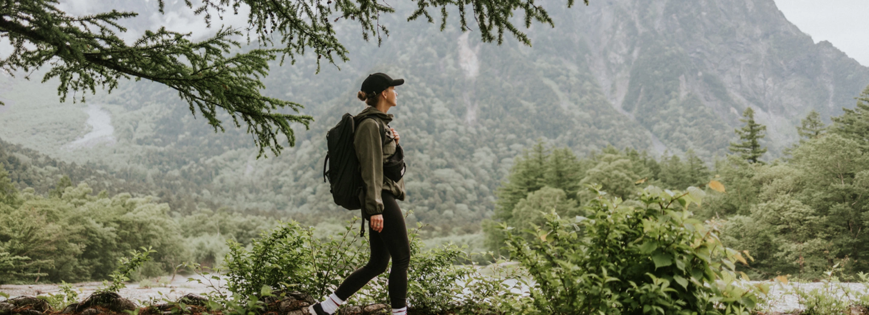 Woman walking outside in nature on a trail with mountains in the background