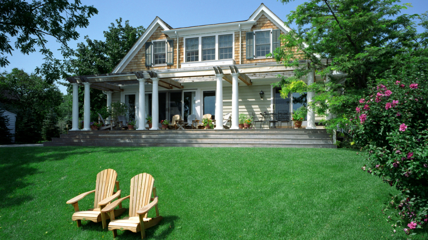 Front of a beautiful home with a lush, green lawn in front of it