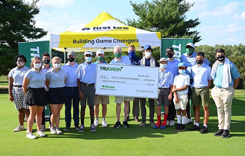 First Tee event  - golfers holding giant check