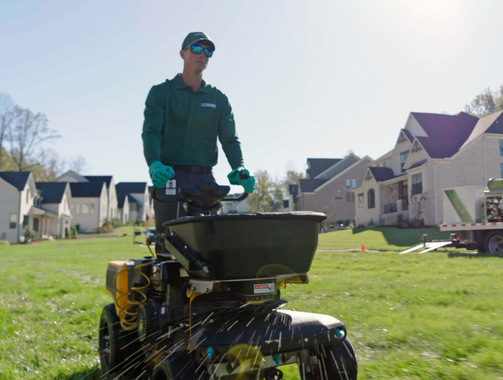 TruGreen specialist treating a lawn on a riding Stinger turf equipment