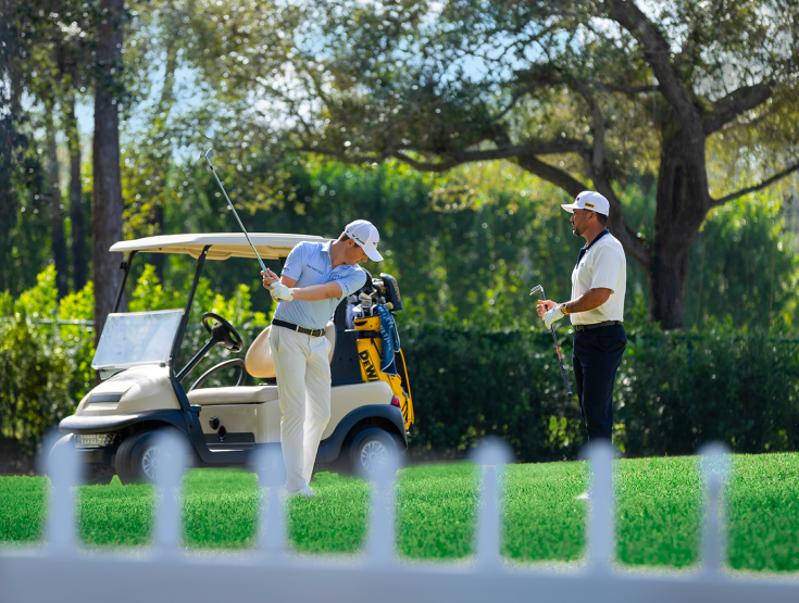 Ben Griffin and Jason Day golfing in front of a golf cart on a golf course quality lawn