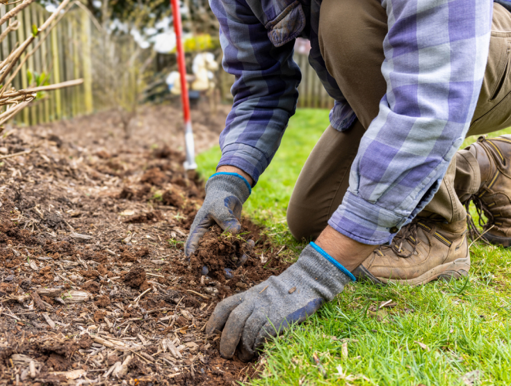 Close-up of someone doing yard work adding mulch around landscaping