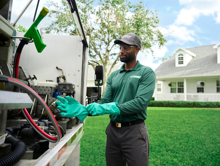 TruGreen specialist at the back of a TruGreen truck preparing to treat a lawn