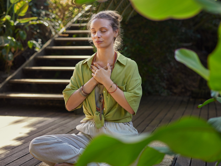 Woman practicing yoga outside surrounded by greenery
